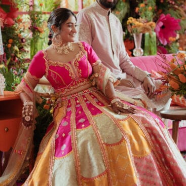 Bride dancing at vibrant Mexican-themed Mehendi with colourful decor, papel picado flags, taco bar, and festive floral arrangements.